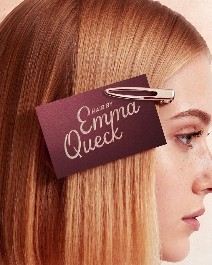 Barber Shops creative ad: Burgundy business card clipped into a redhead's hair with a rose-gold clip