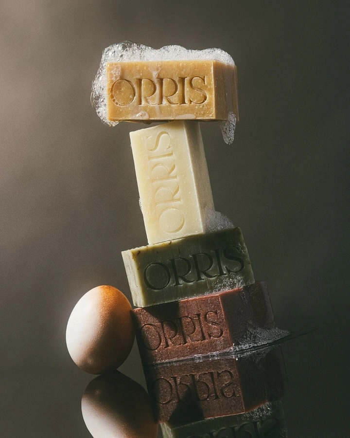 Soap & Bath Products creative ad: Balanced stack of four coloured soap bars with foam beside an egg