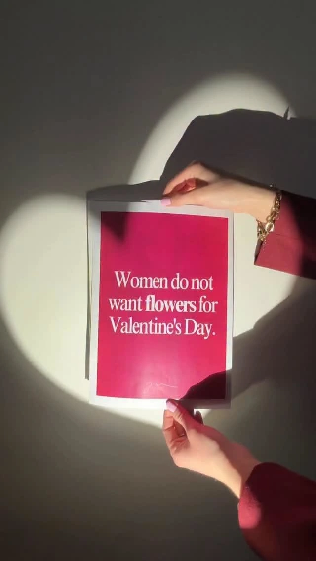 Valentine's Day creative ad: Hands holding a magenta sign in a heart-shaped spotlight