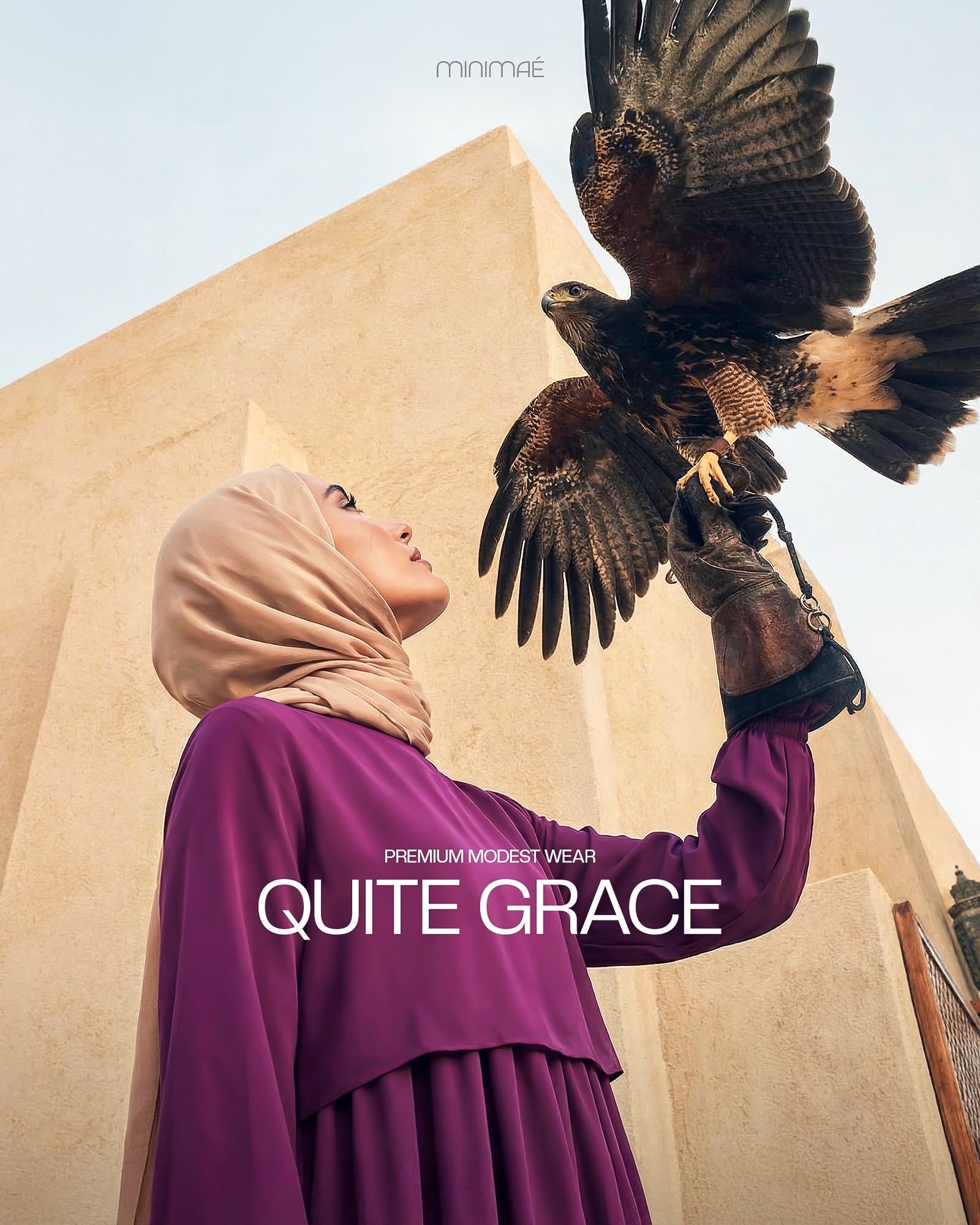 Instagram post: Low-angle shot of a hijab-wearing woman in plum holding a falcon with spread wings on a gloved hand