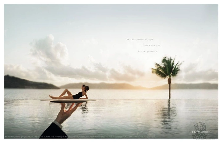 Hotel & Hospitality creative ad: Butler's hand carrying a tray with a sunbathing woman across a calm sea