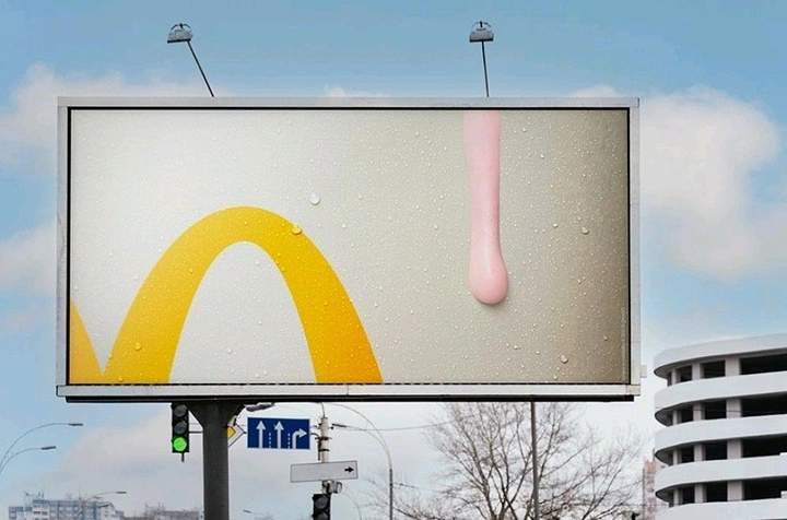 Fast Food creative ad: Cropped golden arch beside a pink shake drip on a frosty surface