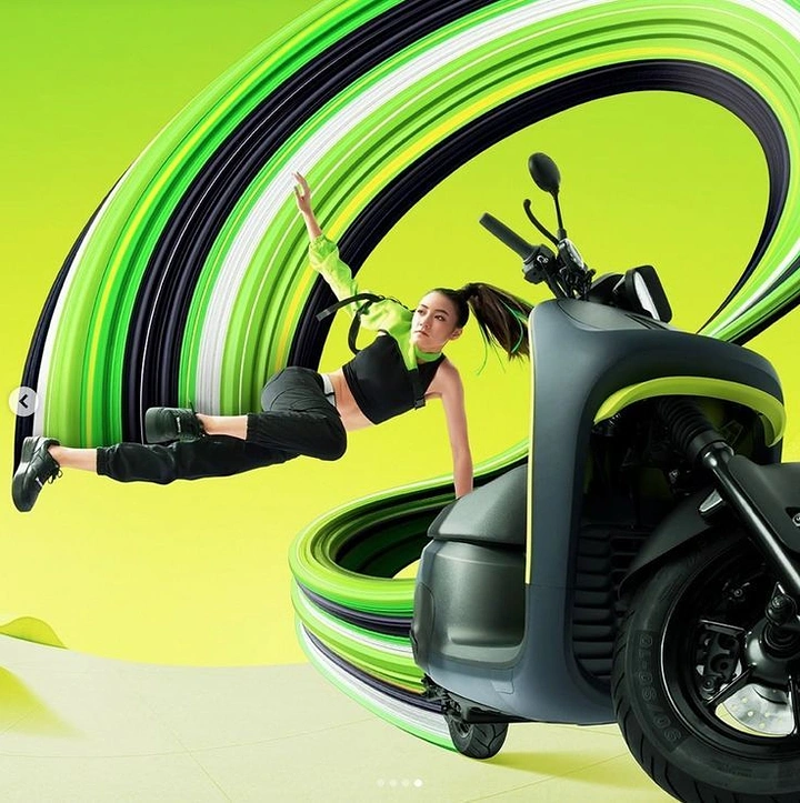 Electric Vehicles creative ad: Female dancer leaping beside an electric scooter within a swirling green ribbon
