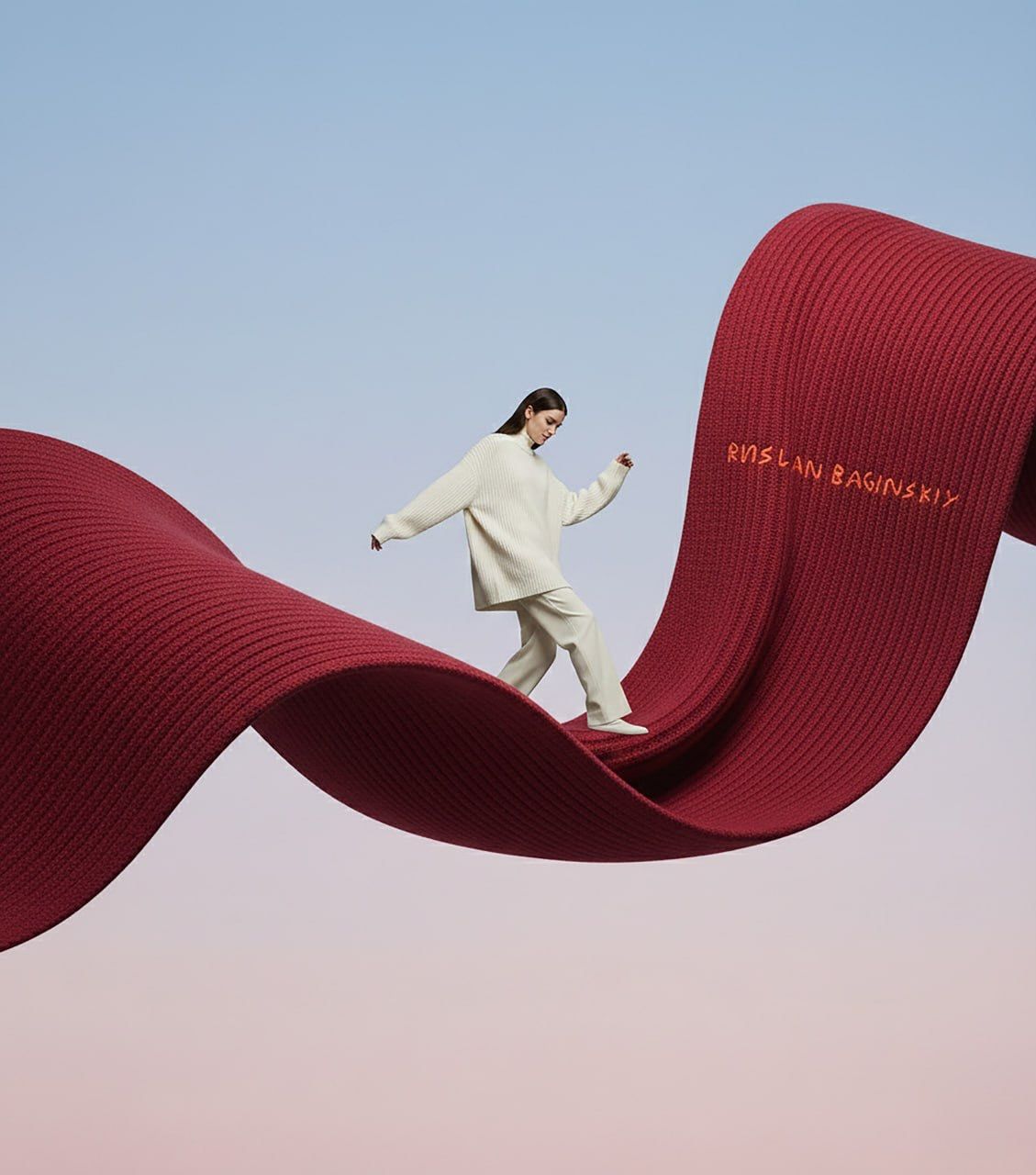 Carousel: Model in cream knitwear walking along a giant undulating red knitted scarf, slide 1