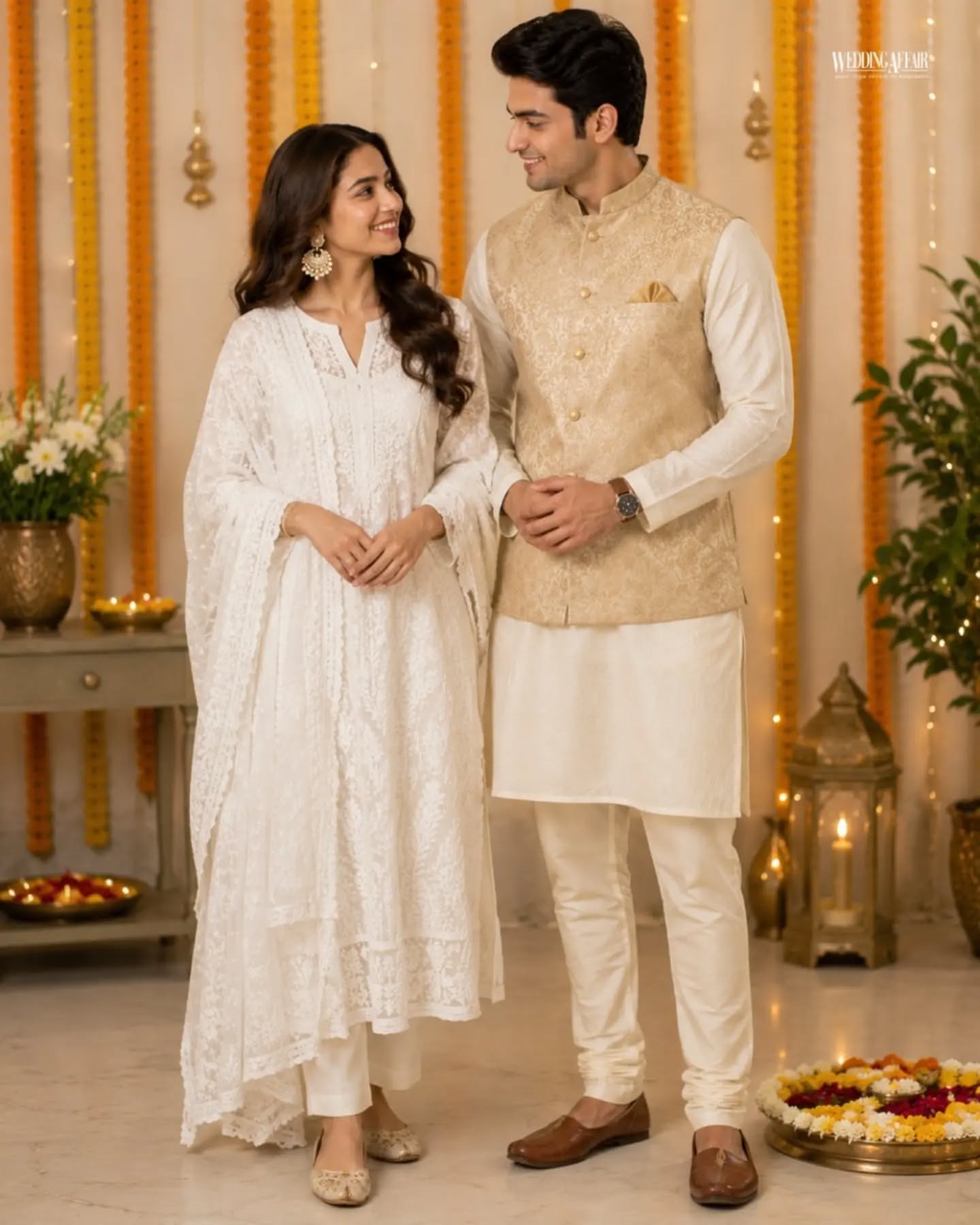 Brother and sister in coordinated pastel ethnic outfits playfully tugging a wrapped gift on a sofa