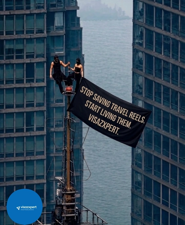 Visa & Immigration creative ad: Masked couple on a skyscraper mast unfurling a black slogan banner