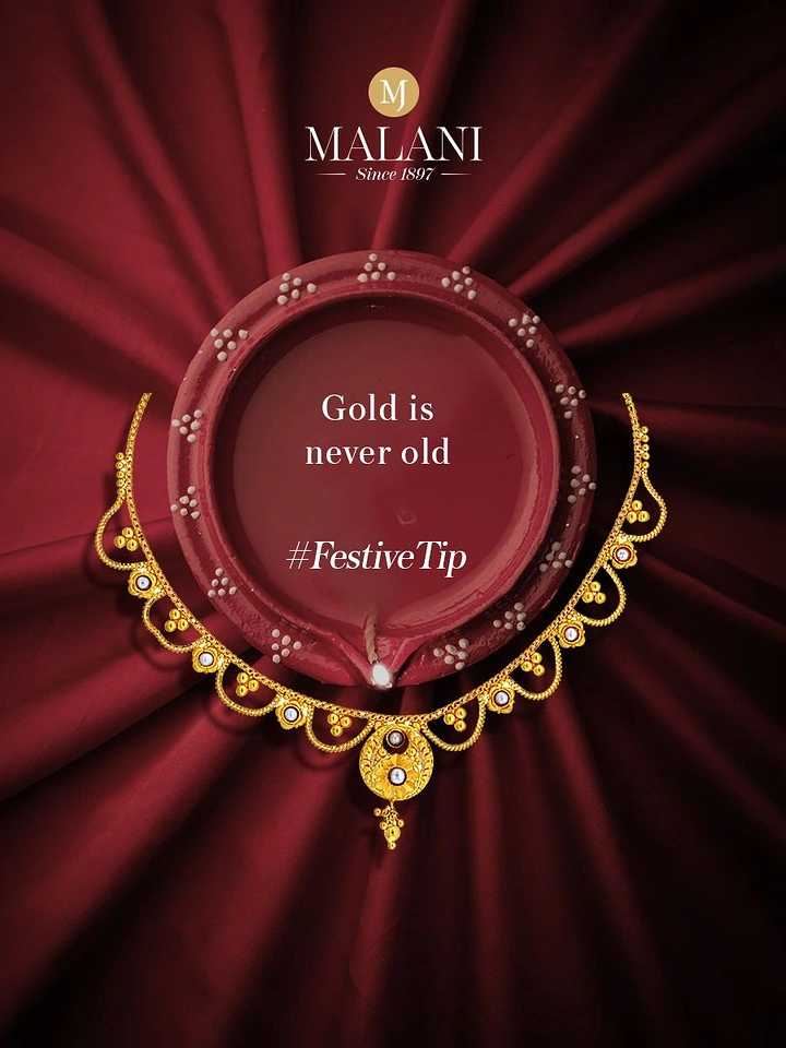 Diwali creative ad: Gold necklace draped around a large red clay diya