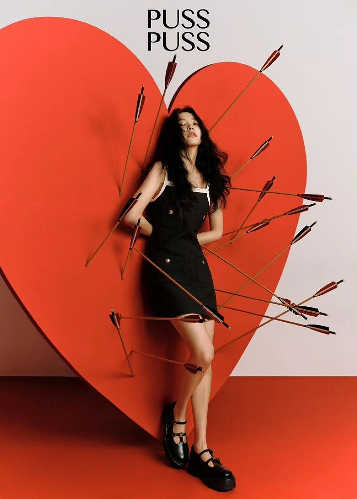 Valentine's Day creative ad: Model in a black dress against a giant red heart pierced by arrows