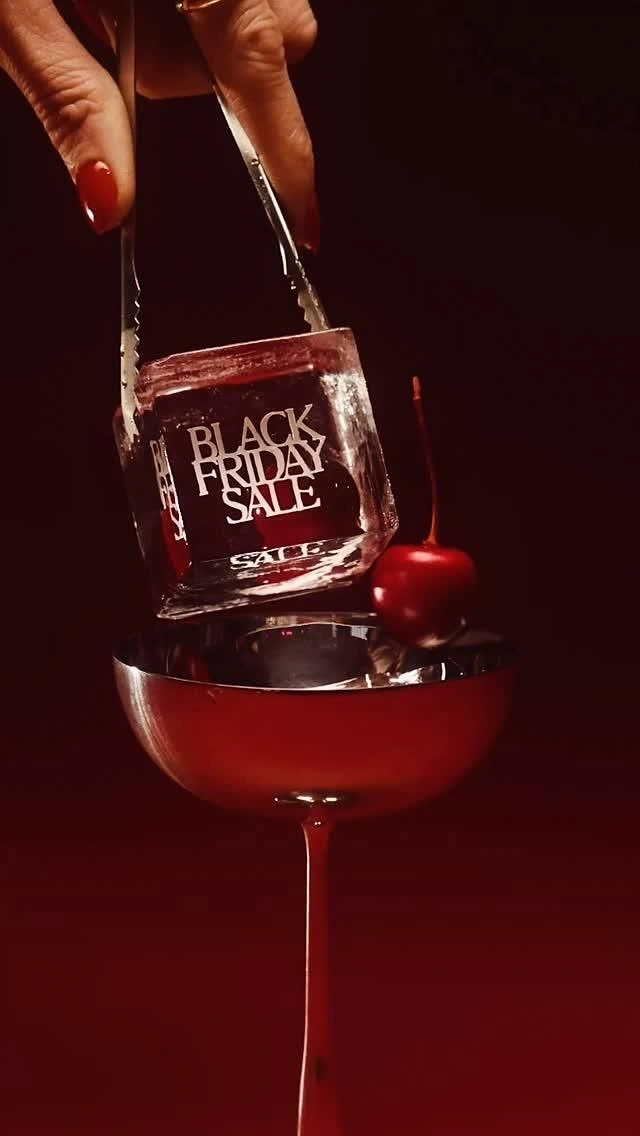 Black Friday creative ad: Hand with tongs placing an engraved ice cube into a red coupe
