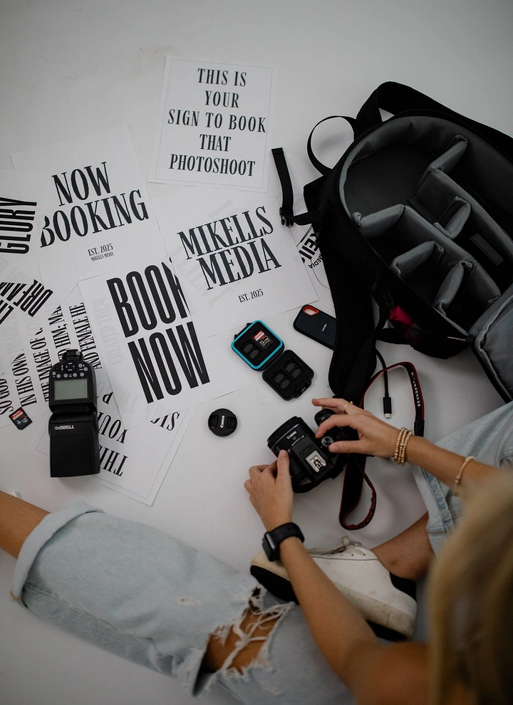 Photography creative ad: Flat-lay of gear and 'book now' prints