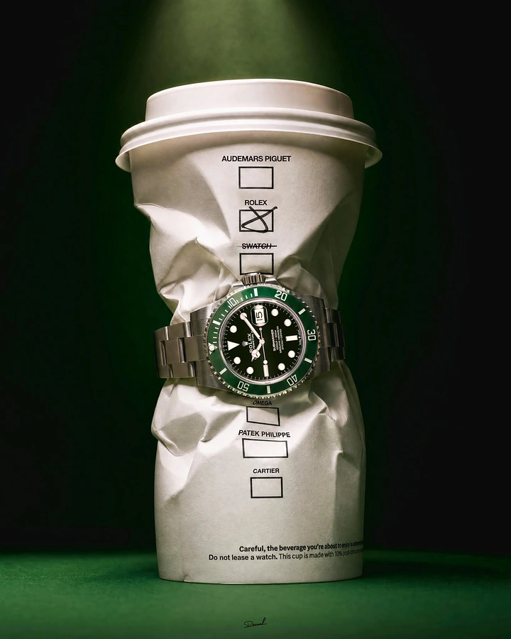 Coffee Shops creative ad: Green-bezel dive watch cinching a crushed paper coffee cup