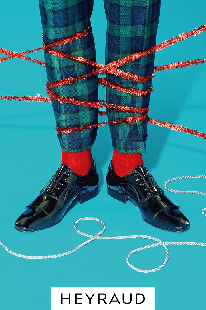 Sneakers & Footwear creative ad: Legs in tartan trousers wrapped in red tinsel, wearing black patent oxford shoes