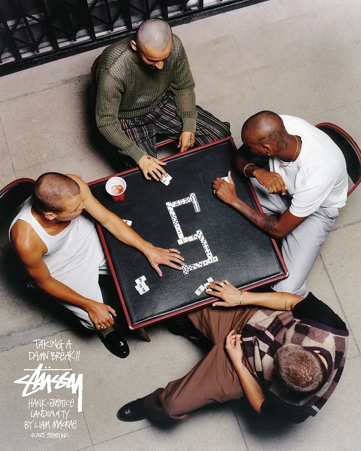 Creative ad: Overhead shot of four men playing dominoes at a black card table