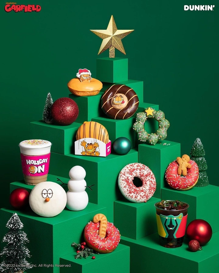 Christmas creative ad: Donuts and drinks arranged on green stepped plinths forming a tree