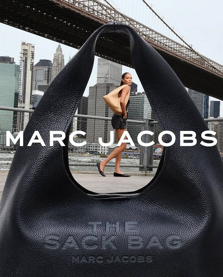 Creative ad: Giant black leather bag whose handle frames a model walking under a bridge