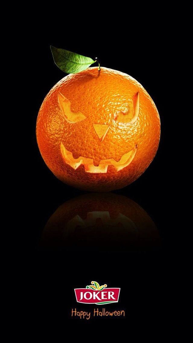 Orange carved like a jack-o'-lantern with a leaf