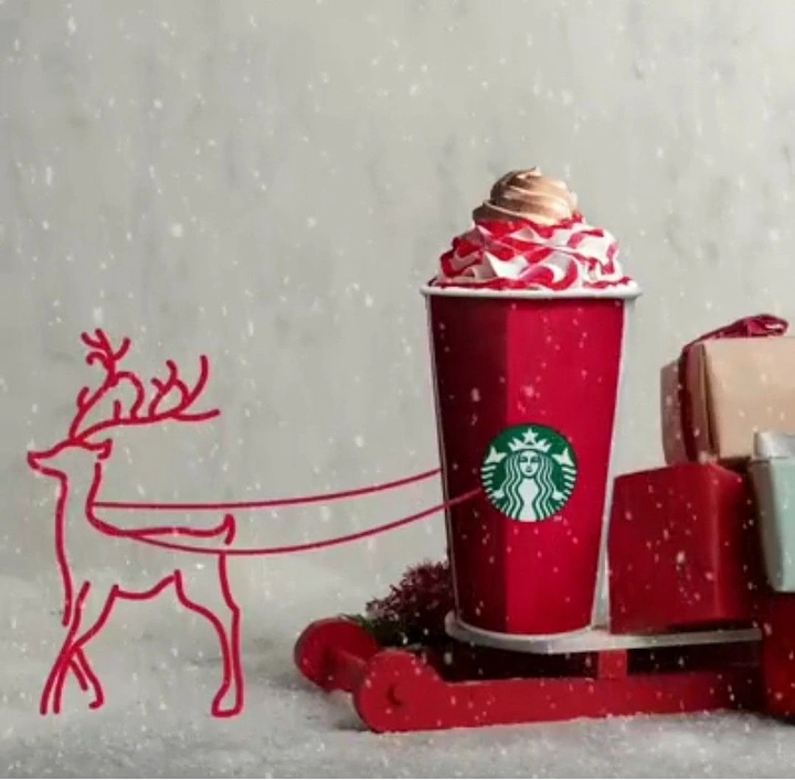 Christmas creative ad: Red holiday cup on a sleigh pulled by a drawn reindeer