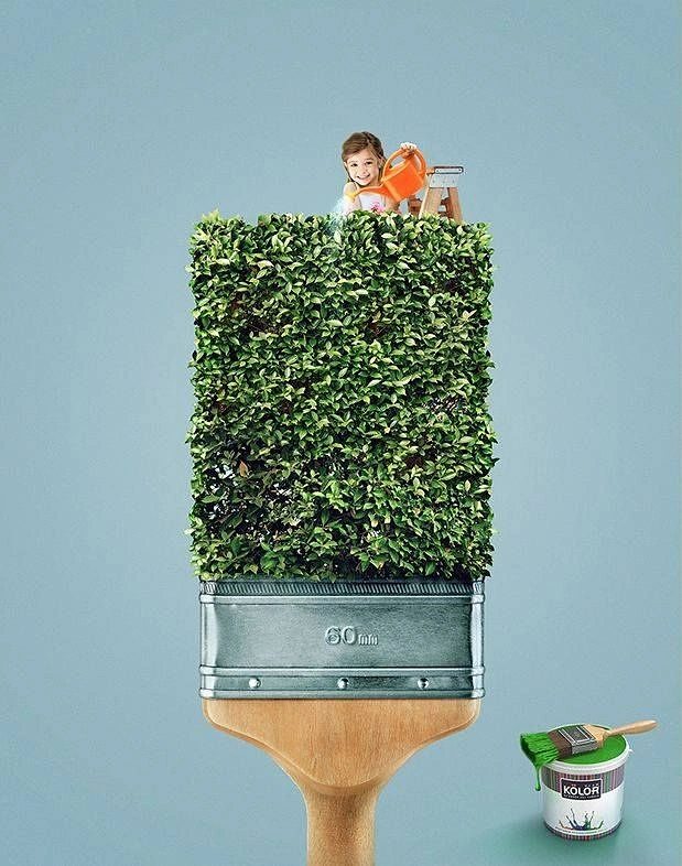 Construction creative ad: Giant paintbrush with trimmed green hedge as bristles, child watering it from a ladder