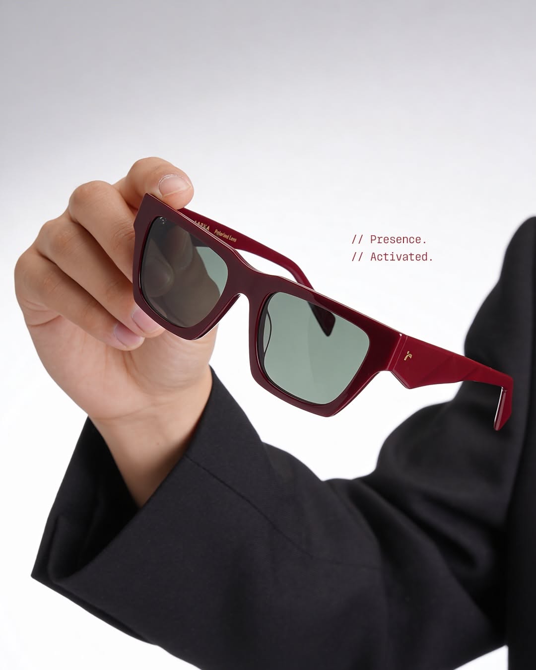 Carousel: Hand resting red acetate sunglasses on a knee in black trousers, slide 4
