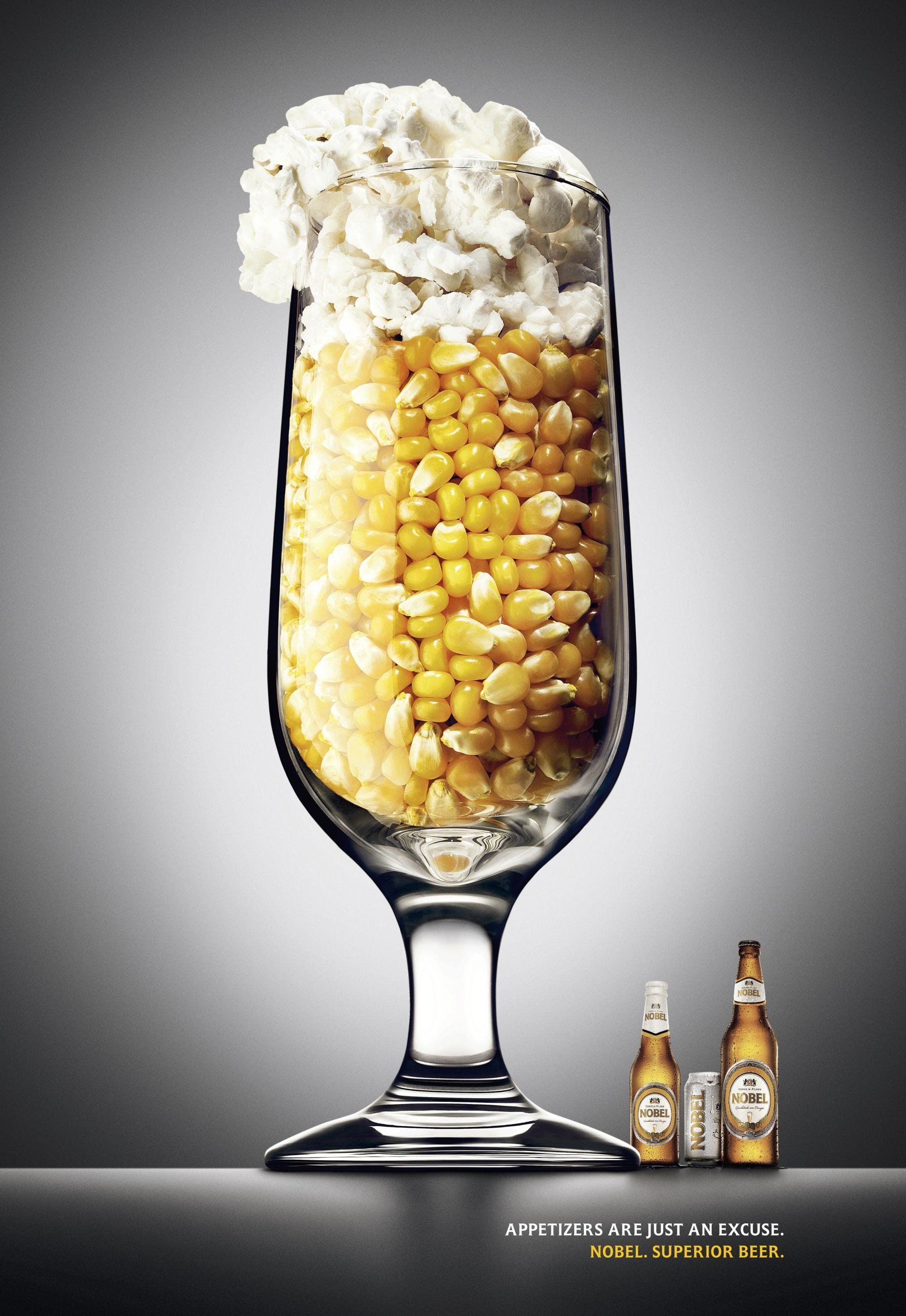 A stemmed beer glass filled with corn kernels and topped with popcorn as foam