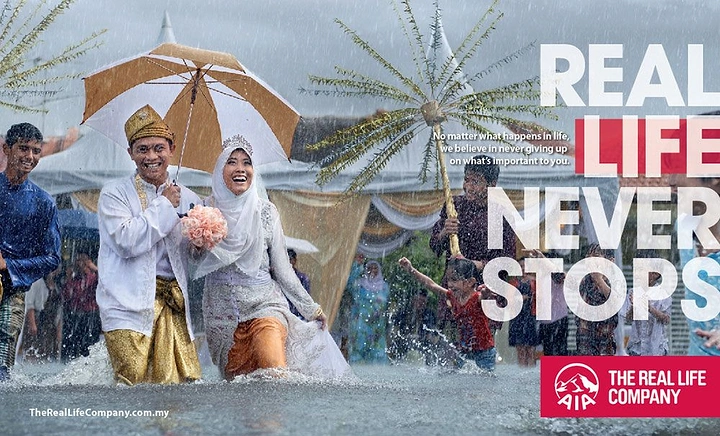 Insurance creative ad: Malay bride and groom laughing while wading through a flooded street in the rain