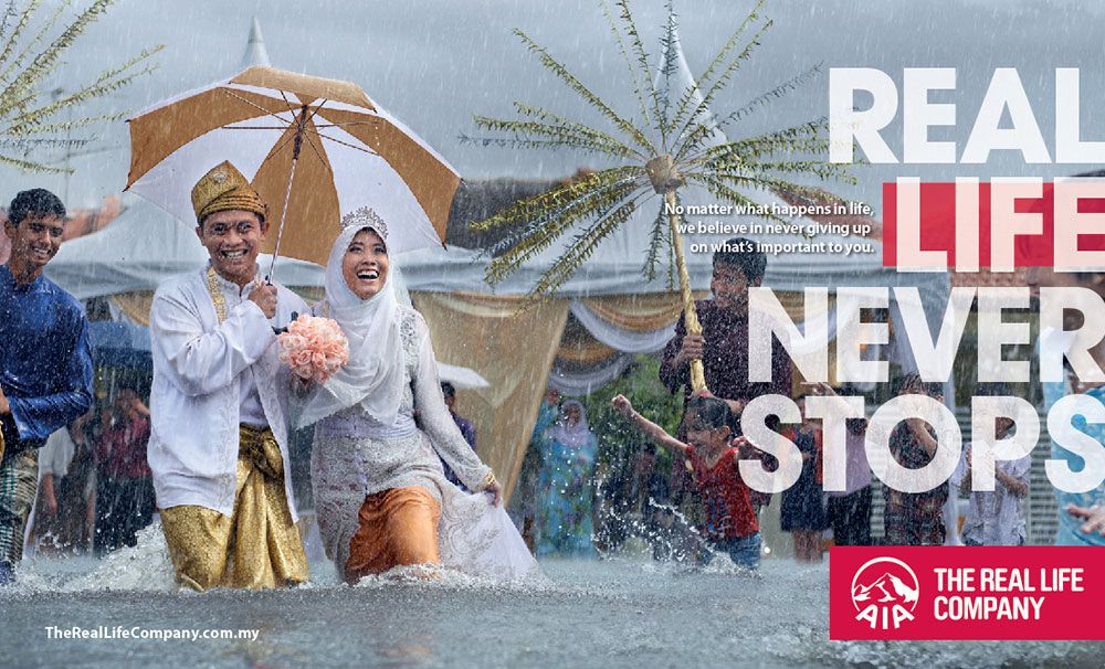 Banner: Malay bride and groom laughing while wading through a flooded street in the rain