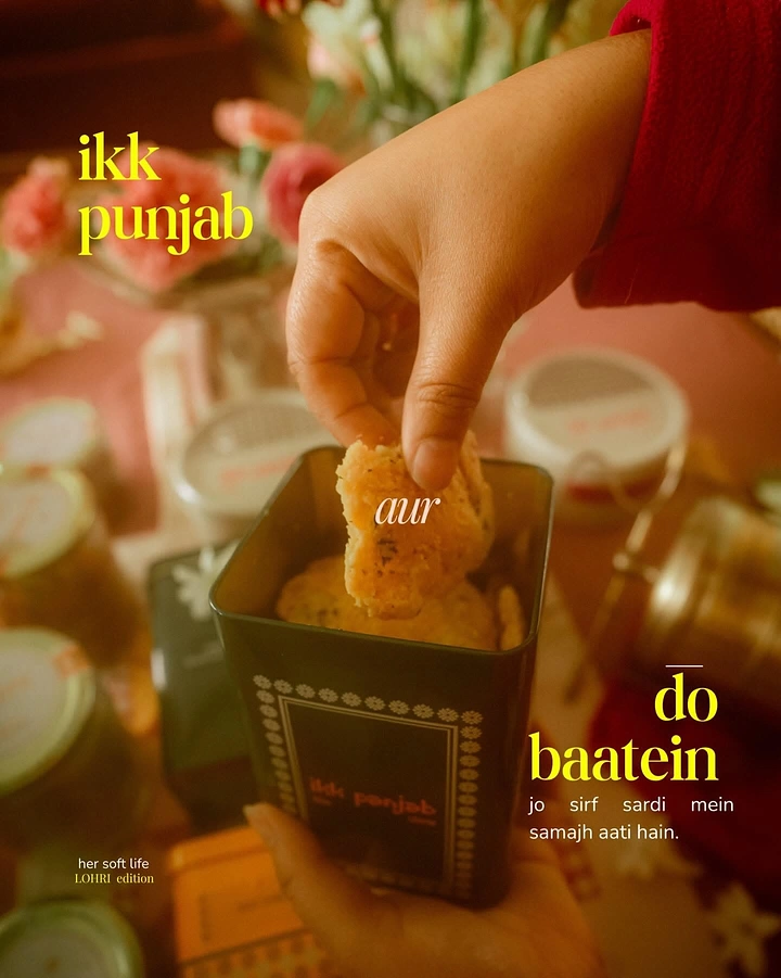 Lohri creative ad: Hand lifting a savoury biscuit from a dark patterned gift tin
