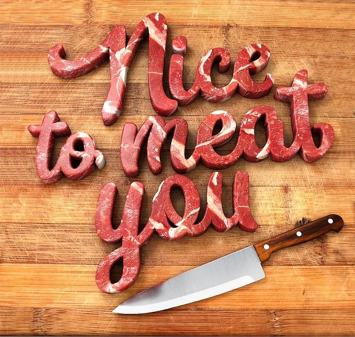 Meat & Seafood Shops creative ad: Script lettering sculpted from raw marbled meat on a cutting board