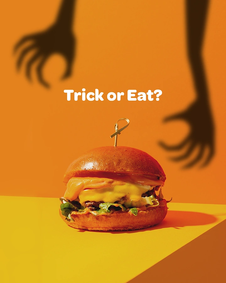 Halloween creative ad: Cheeseburger with shadowy monster hands reaching toward it