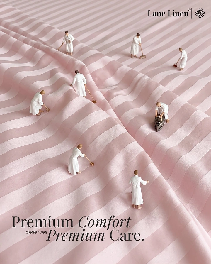 Mattress & Bedding creative ad: Miniature attendants cleaning and ironing a pink striped bedsheet