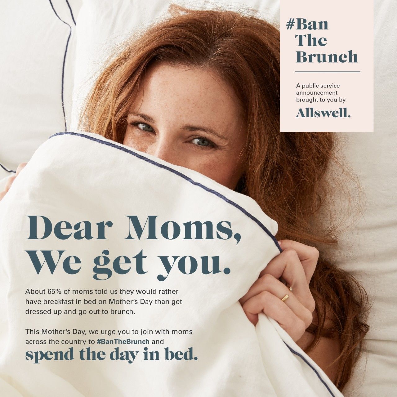 Red-haired woman peeking over a white duvet in bed