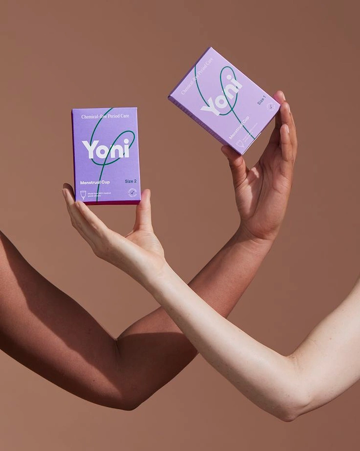 Period Care & Feminine Hygiene creative ad: Two crossed arms of different skin tones holding lavender menstrual cup boxes