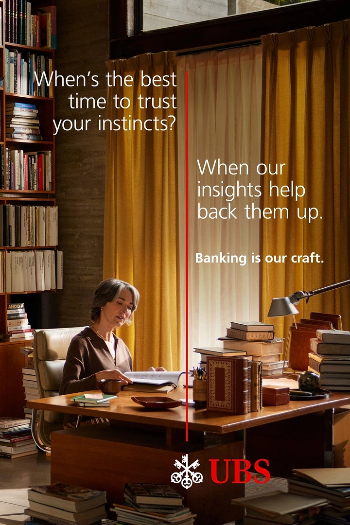Creative ad: Older woman reading at a book-laden desk in a library study