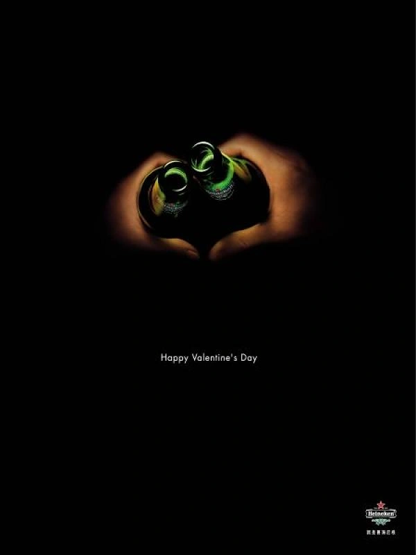 Valentine's Day creative ad: Hands forming a heart around two green beer bottle necks