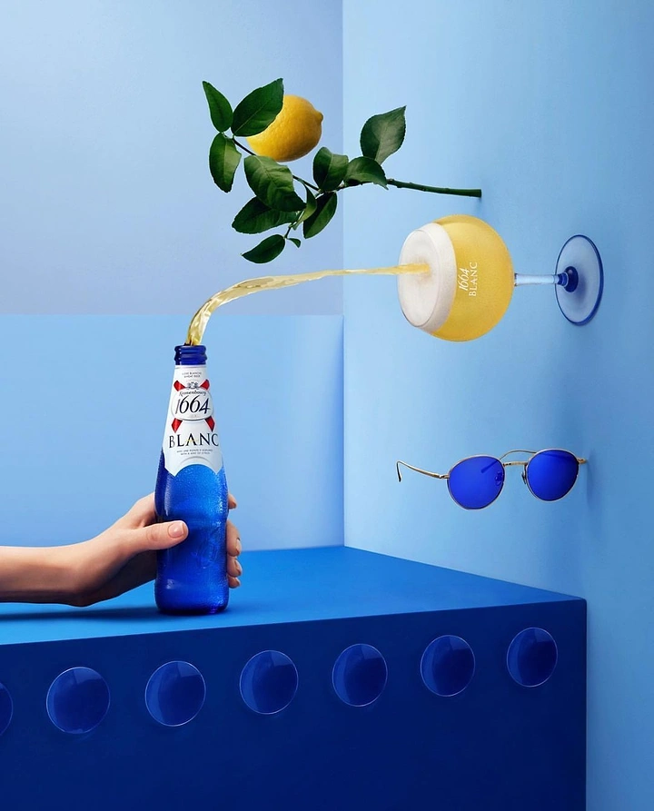 Beer, Wine & Spirits creative ad: Hand-held blue beer bottle pouring an arc into a wall-mounted glass