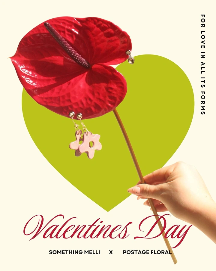 Valentine's Day creative ad: Hand holding a red anthurium with pink flower earrings hung from it