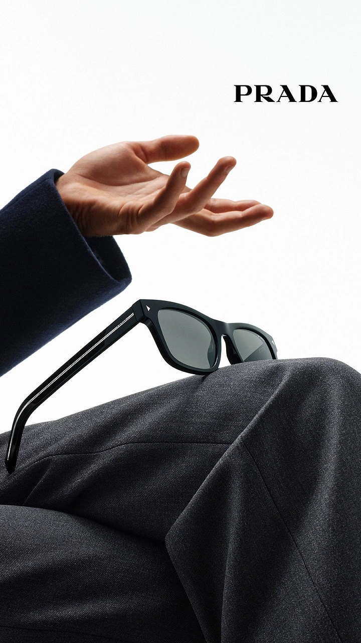 Creative ad: Black sunglasses resting on a suited knee beneath an open hand