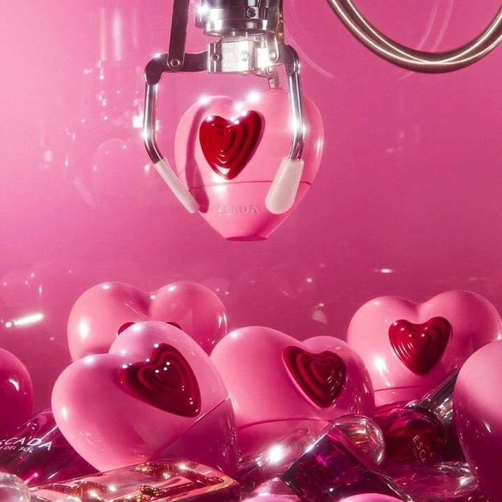 Valentine's Day creative ad: Claw machine lifting a pink heart-shaped perfume bottle from a pile