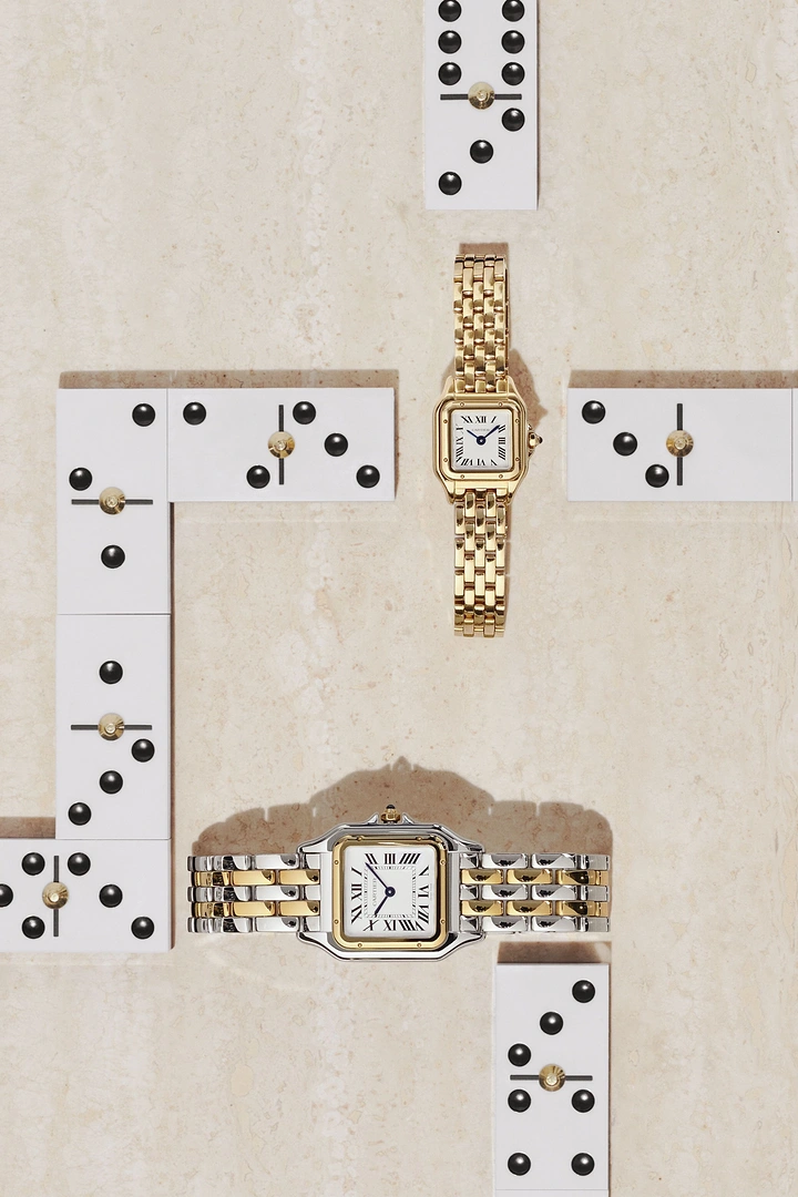 Creative ad: Two square luxury watches laid among dominoes on travertine