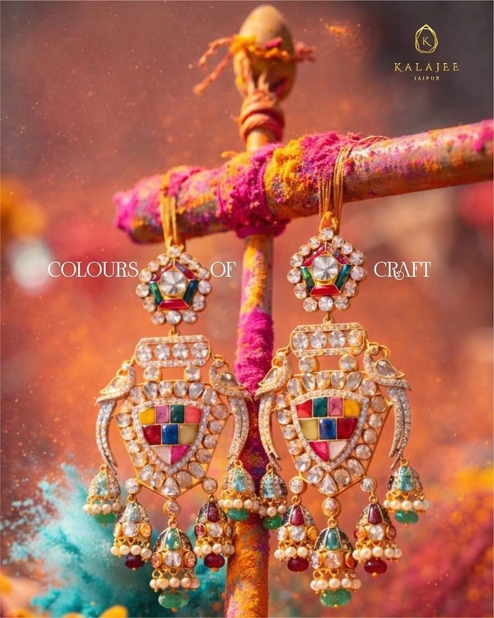 Holi creative ad: Navratna kundan chandelier earrings hanging from a gulal-smeared wooden post