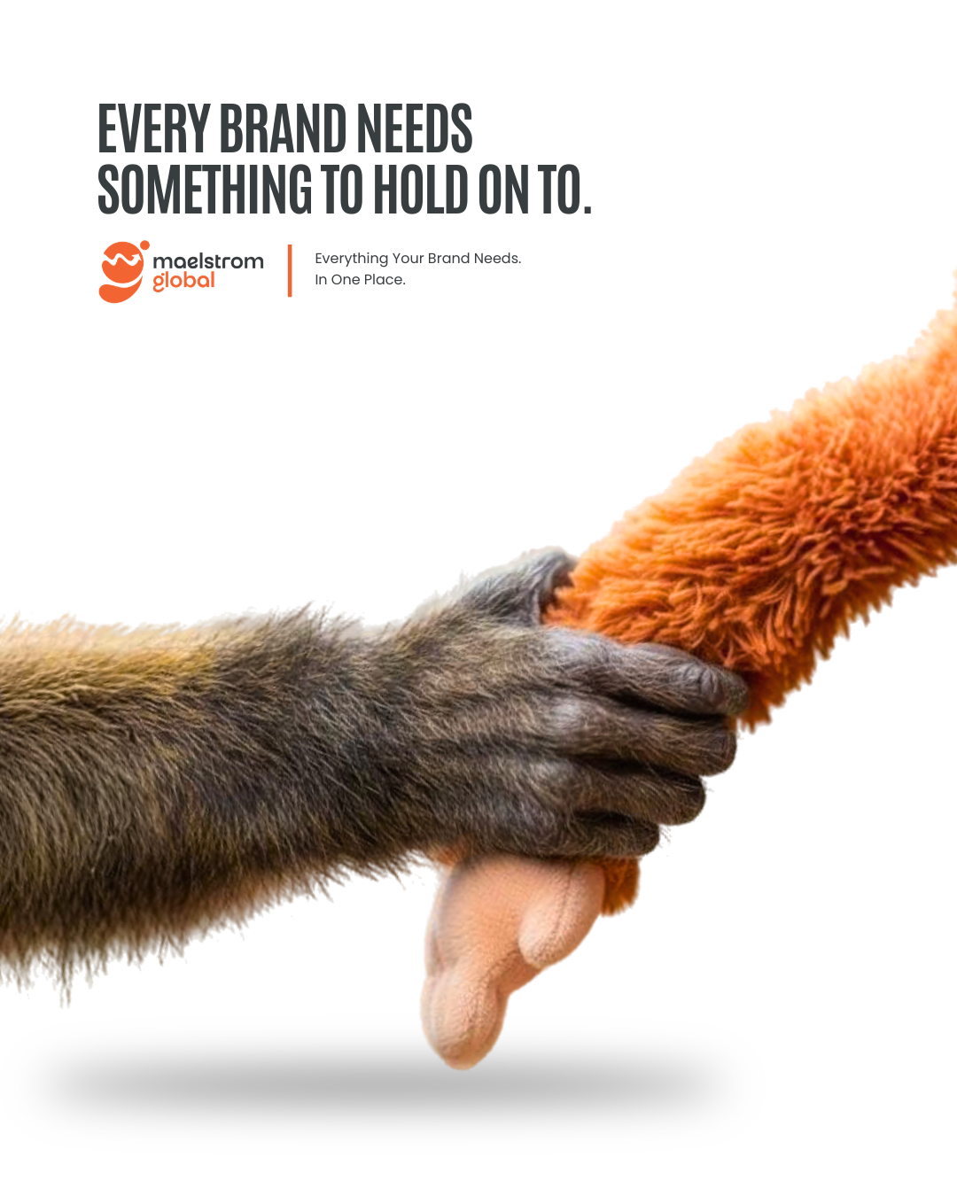 Real monkey hand gripping an orange plush toy's arm