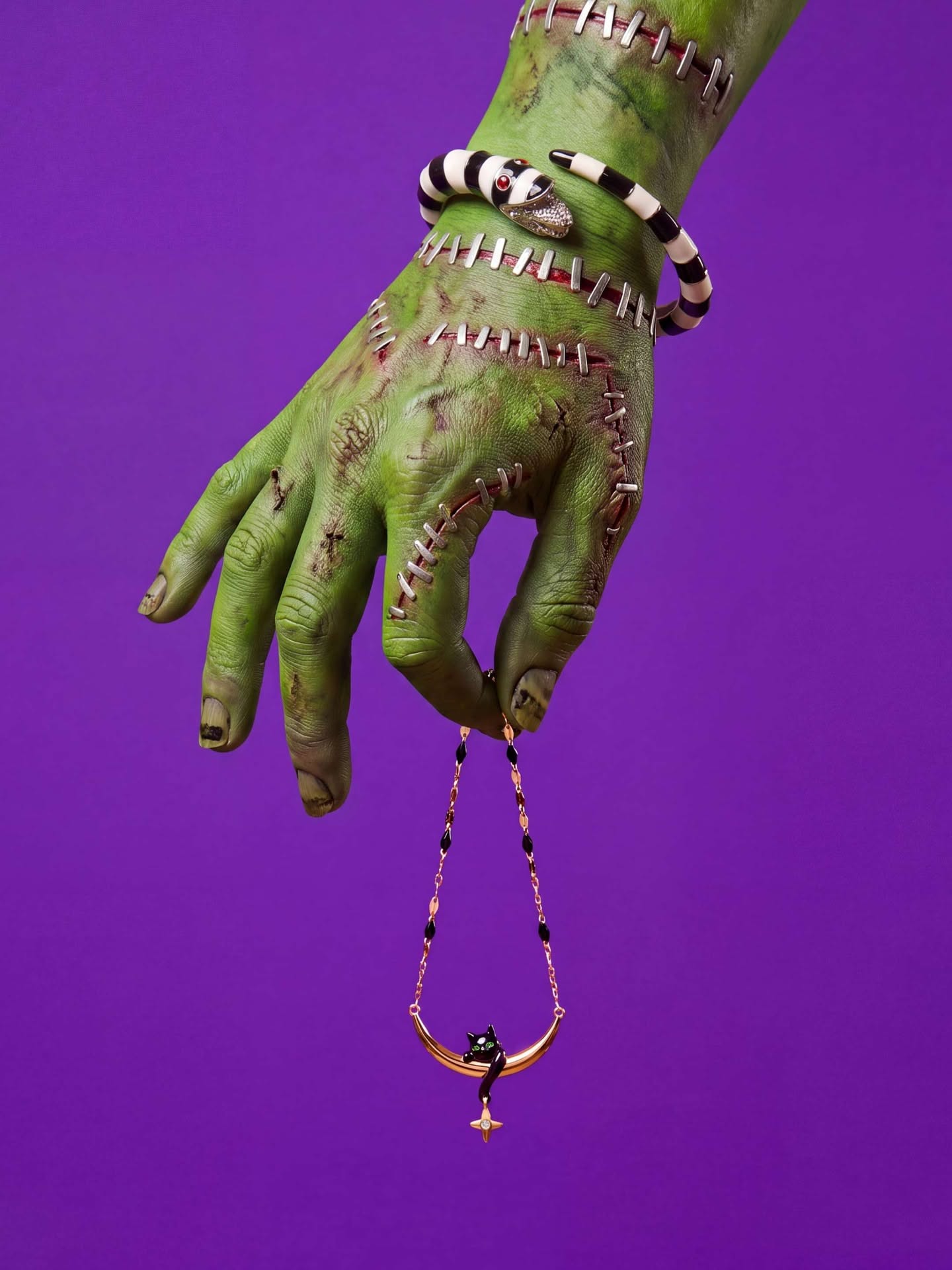Green witch hand holding a vampire-fang pendant necklace