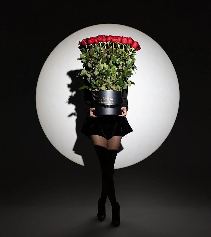 Florists creative ad: Person concealed behind a cylindrical box of red roses