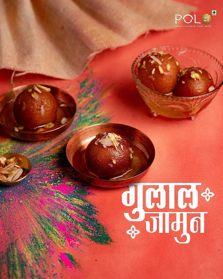 Holi creative ad: Gulab jamun in copper and glass bowls beside gulal streaks