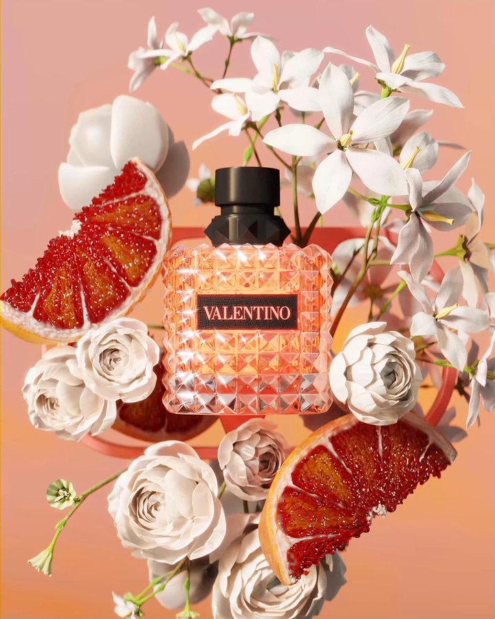 Creative ad: Studded coral perfume bottle among flowers and blood orange
