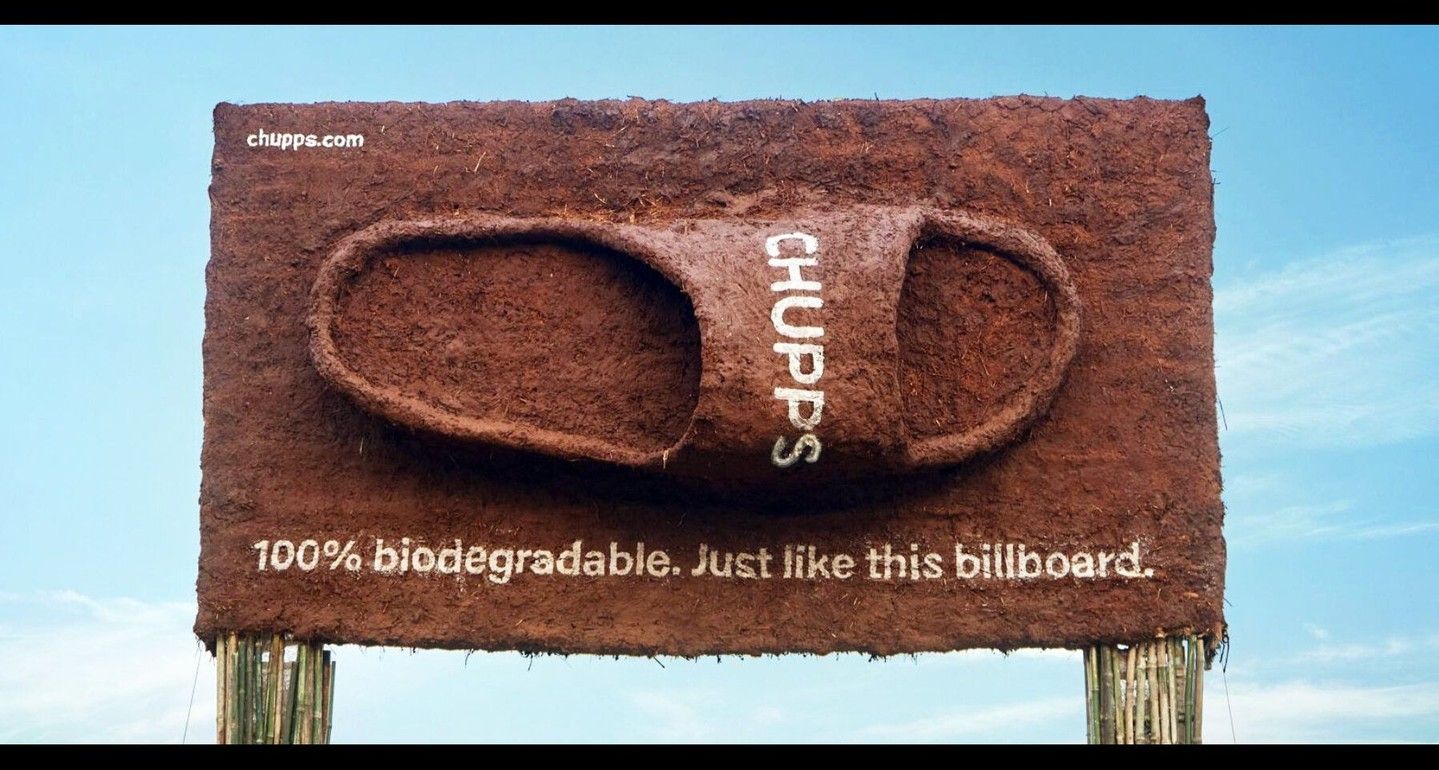 Banner: Giant slide sandal sculpted from mud on a mud billboard