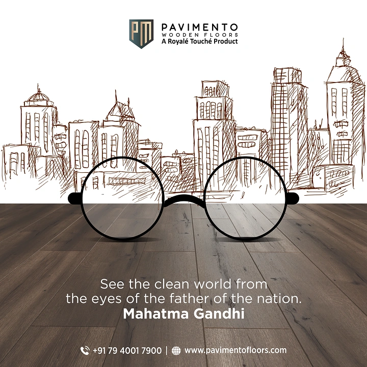 Gandhi Jayanti creative ad: Gandhi-style round glasses resting on a wooden floor in front of a sketched skyline