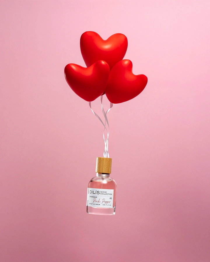 Valentine's Day creative ad: Perfume bottle lifted by three red heart balloons