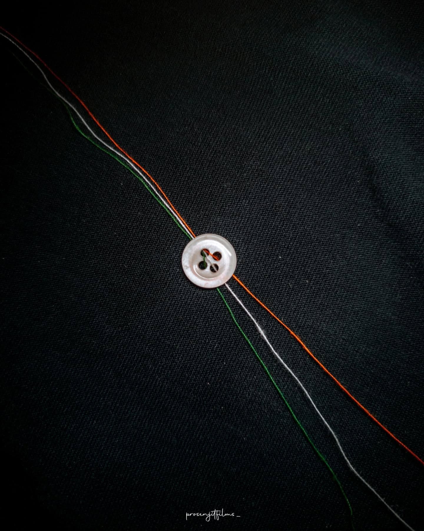 Macro shot of a needle threaded with saffron, white and green threads