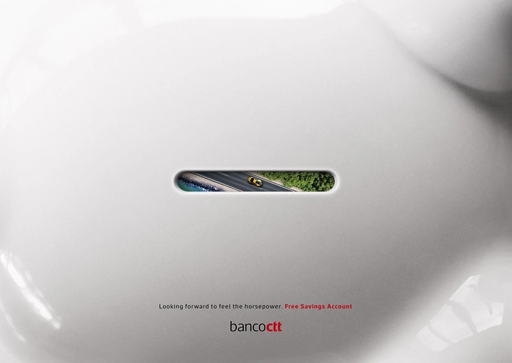 Creative ad: Close-up of a white piggy bank's coin slot revealing an aerial view of a sports car on a coastal road